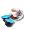 Tazzina di caffè espresso Bacca Rossa con chicchi di caffè tostato sul piattino. Affianco una capsula compatibile Dolce Gusto di caffè Decaffeinato.
