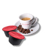 Tazzina di caffè espresso Bacca Rossa con chicchi di caffè tostato sul piattino. Affianco una capsula compatibile Dolce Gusto di caffè Tramonto.